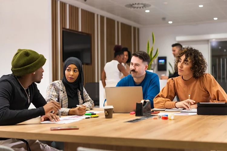 Workers talking at common coworking space tables, busy multiethnic businessmen and businesswomen working together in the space of coworking, diverse staff of employees (gettyimages/Divulgação)