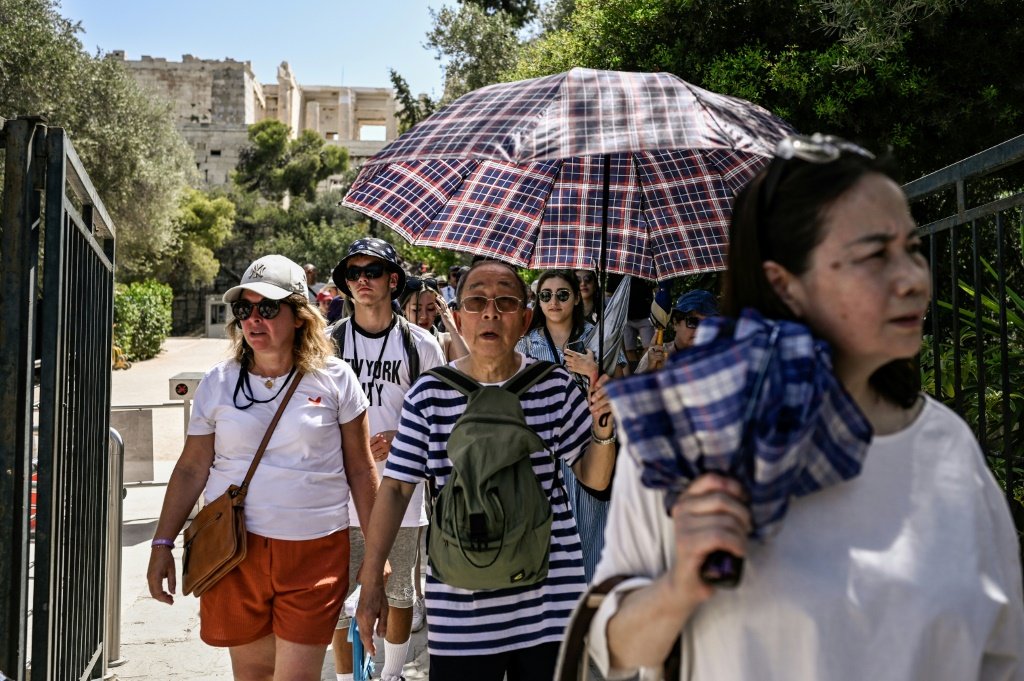Turistas se protegem do calor na Acrópole, em Atenas, em 14 de julho de 2023 (AFP/AFP)