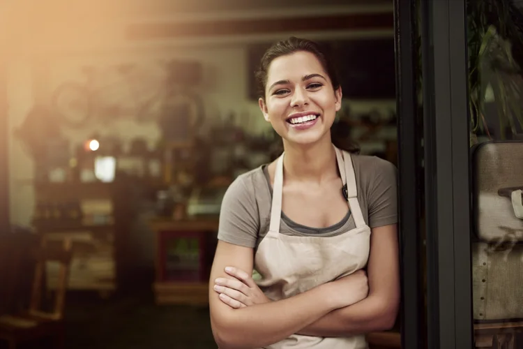 Portrait of a confident young woman standing in the doorway of a coffee shop (Cecilie_Arcurs/Getty Images)