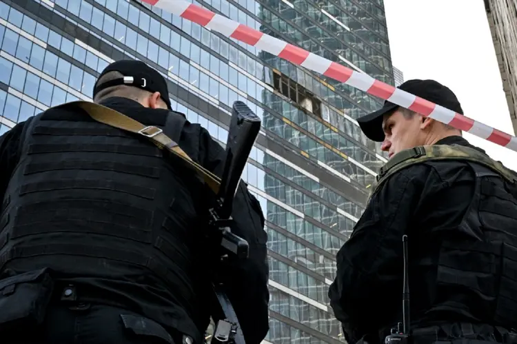 Dois policiais observam edifício atingido por drone ucraniano em bairro de negócios de Moscou (AFP/AFP Photo)
