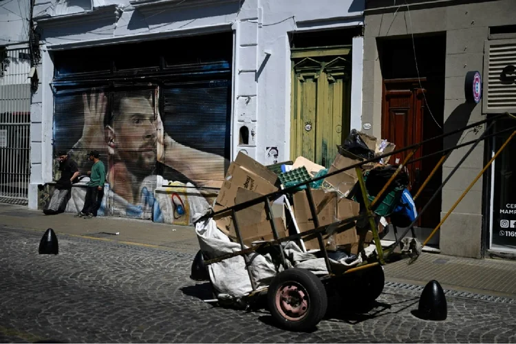 Argentina: catadores de lixo ao lado de um grafite de Lionel Messi em Buenos Aires (Javier Tovar/AFP)