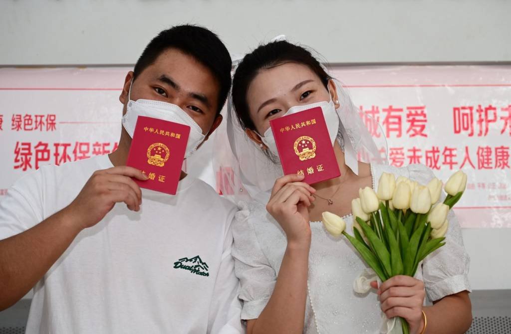 Recém-casados mostram certidões de casamento em Neijiang, na China  (Tang Mingrun/Getty Images)