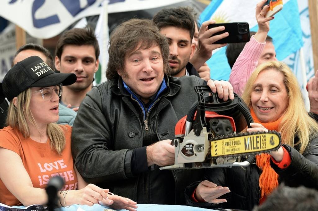 Javier Milei com motoserra na mão, ao lado de Karina Milei (à dir.) e da candidata ao governo da província de Buenos Aires, Carolina Piparo, em comício em La Plata, Argentina, em 12 de setembro de 2023 (AFP/AFP)