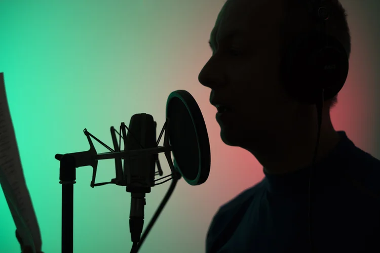 Voiceover artist voice actor in vocal recording studio with larg diaphragm microphone and antipop shield. (eduardolive/Getty Images)