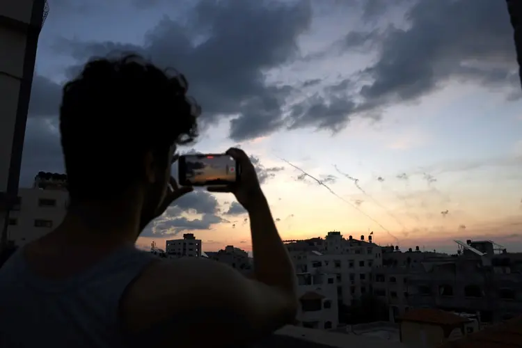 Uma pessoa grava em seu celular um vídeo do lançamento de um míssil de Gaza contra Israel, em 7 de outubro de 2023

 (AFP/AFP)