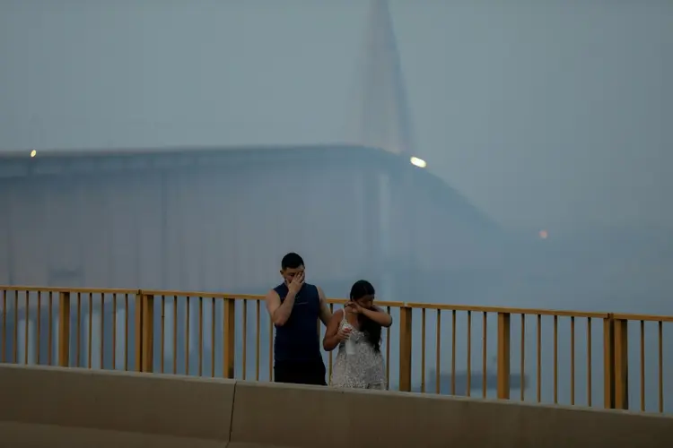 Um casal atravessa uma ponte em Manaus, envolto em nuvem tóxica de fumaça de incêndios, em 13 de outubro de 2013 (AFP/AFP)