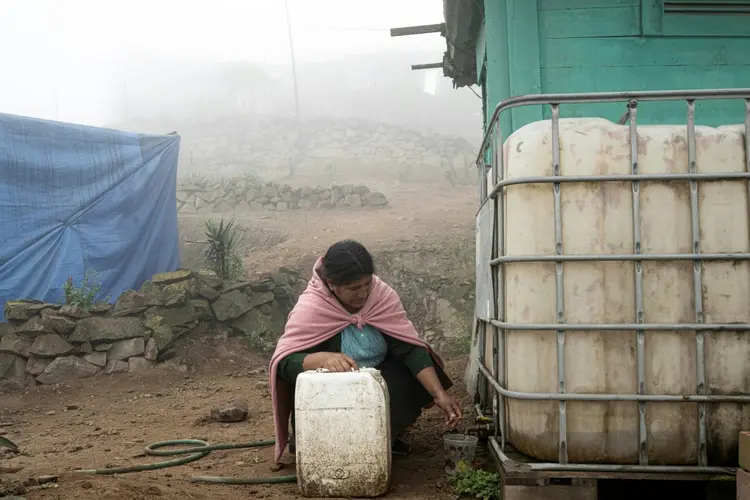 A mãe de Sofía Llocclla Pellaca, Cristina Pellaca Llocclla, tira água de um tanque no distrito Villa María del Triunfo, nos arredores de Lima, em 7 de outubro de 2023 (AFP/AFP)