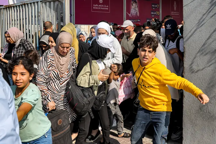 Pessoas passam por portão na fronteira entre Gaza e Egito, na quarta, 1º
 (Mohammed Abed/AFP)