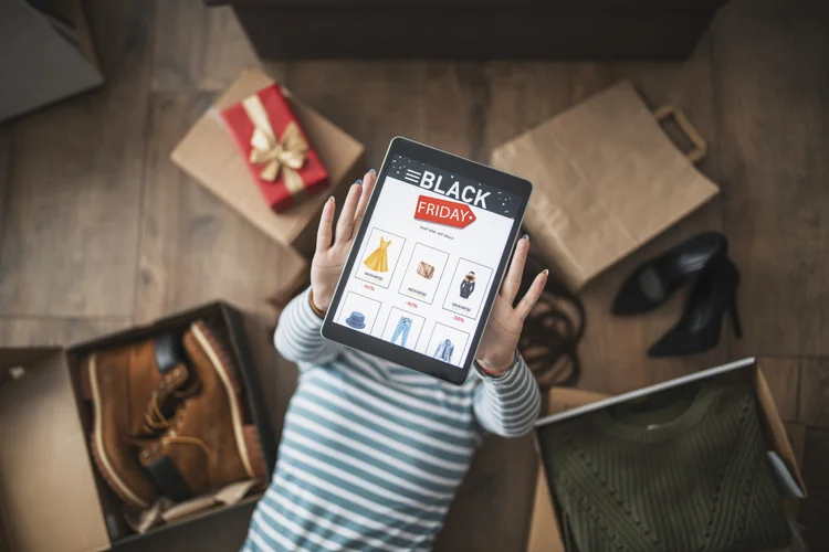 Unrecognisable woman hodling digital tablet with black friday sale page. (ArtistGNDphotography/Getty Images)