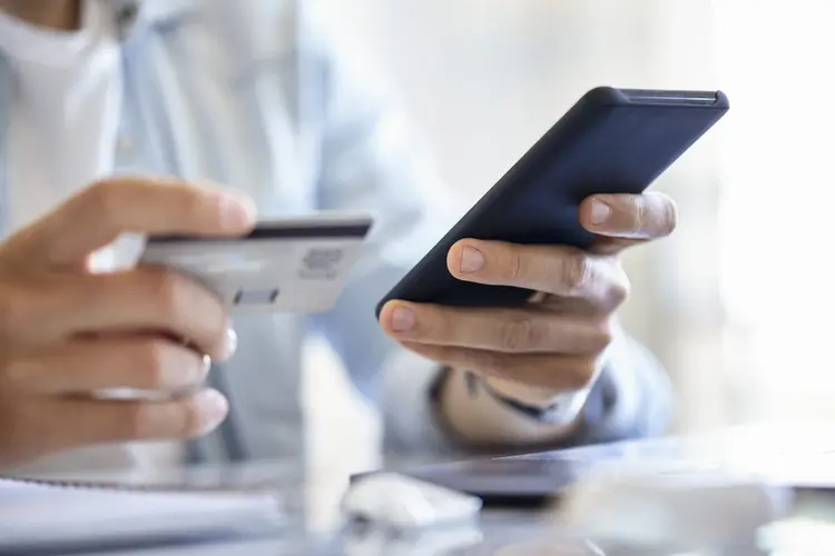 Pessoa realiza pagamentos via aplicativos usando o smartphone. (Mindful Media/Getty Images)