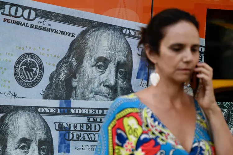 Mulher passa por imagem de notas de dólar em Buenos Aires (Luis Robayo/AFP)