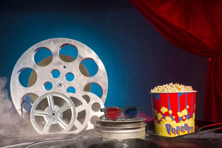 Rolos de filme velhos, pipoca e óculos 3d na mesa.  (unomat/iStockphoto)