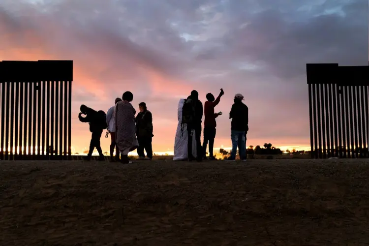 Imigrantes haitianos diante do muro fronteiriço entre México e Estados Unidos em Yuma, no Arizona (Agence France-Presse/AFP Photo)