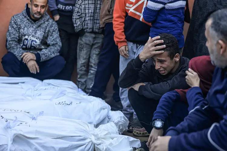 Jovem chora pelos corpos das famílias Salah e Abu Hatab, mortos quando a tenda onde se abrigavam foi atingida por bombardeios israelenses (AFP/AFP)