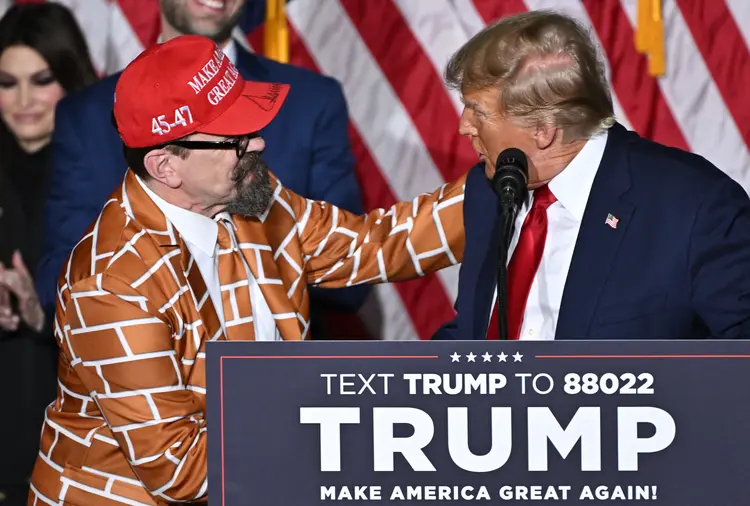 
Donald Trump cumprimenta apoiador vestido com roupa de "muro", em referência à barreira contra imigrantes na fronteira, defendida pelo ex-presidente (Jim Watson/AFP)