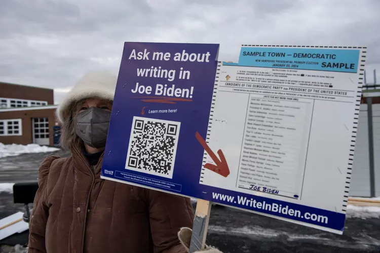 Apoiadora de Biden com cartaz que mostra como votar nele, em Hampton, New Hampshire
 (Joseph Prezioso/AFP)