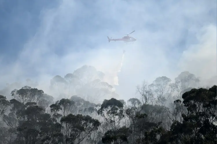 Um helicóptero das Forças Armadas colombianas lança água para combater um incêndio florestal em Bogotá (AFP Photo)
