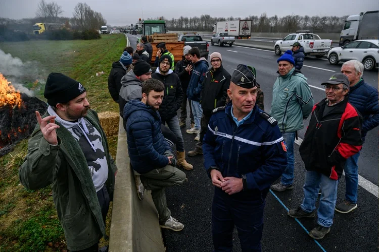 Agricultores conversam com um policial durante um bloqueio de rodovia, nos arredores de Toulouse, sul da França (Julien Girault/AFP Photo)