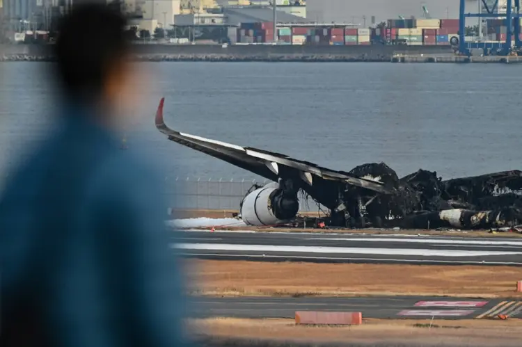 Homem observa os restos do avião no aeroporto de Haneda, Tóquio: todos ocupantes da pequena aeronave morreram (AFP/AFP)