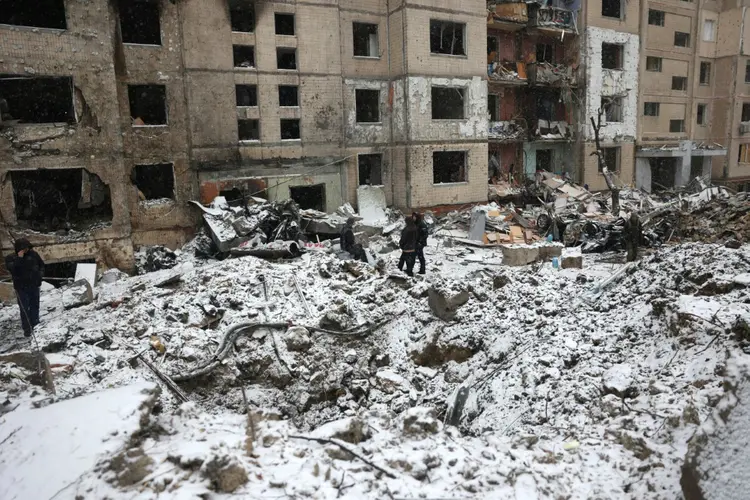 Policiais e moradores examinam os danos a um arranha-céus destruído depois de um ataque russo com mísseis no centro de Kiev, em 3 de janeiro de 2024 (AFP/AFP)
