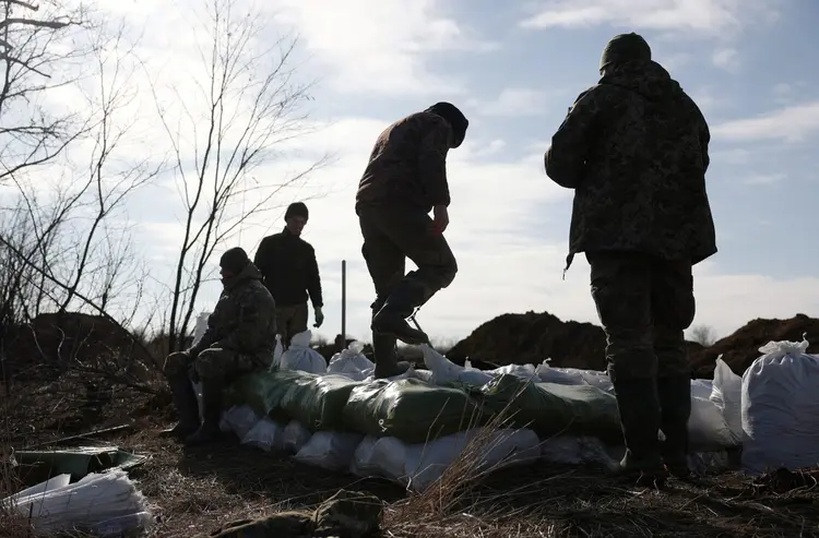 Militares ucranianos empilham sacos de terra para construir uma fortificação não muito longe da cidade de Avdiivka, na região de Donetsk, em meio à invasão russa da Ucrânia nesse sábado, 17 (AFP/AFP)