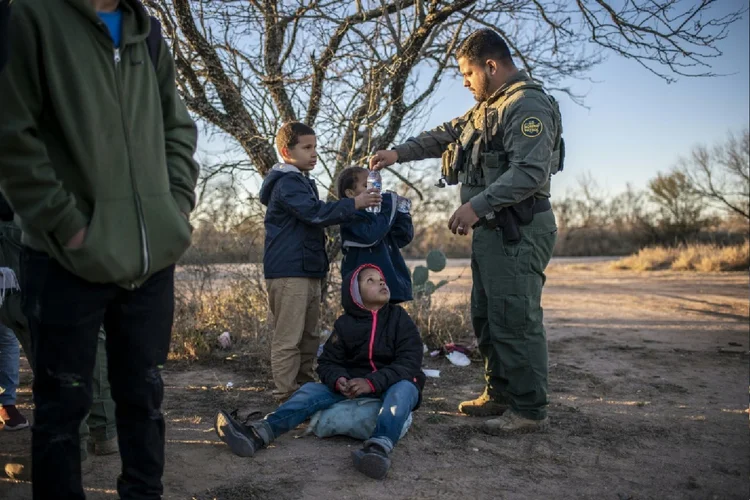 Um oficial da Patrulha de Fronteira dá água a um grupo de menores não acompanhados após serem detidos perto da estrada em 4 de fevereiro de 2024, na periferia de Eagle Pass, Texas, após atravessar o Rio Bravo (Moises Ávila/AFP Photo)