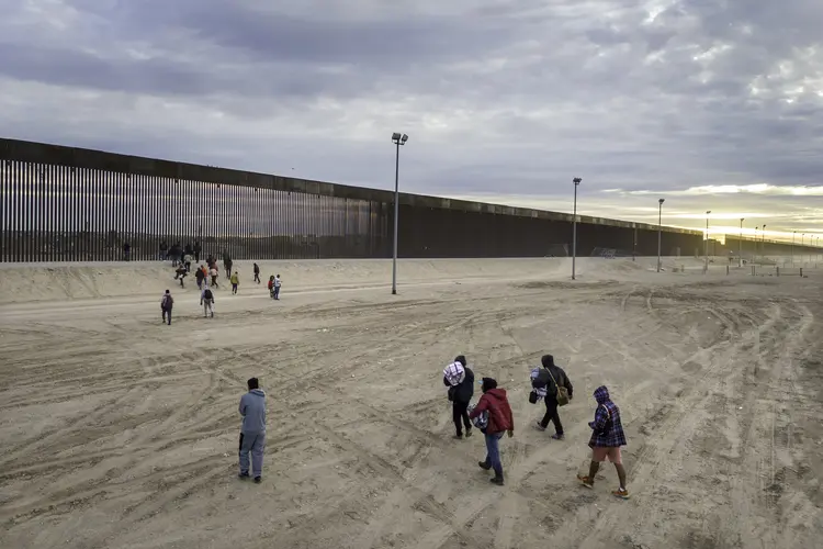 Imigrantes caminham em direção à barreira na fronteira entre EUA e México entre Ciudad Juarez e El Paso, em 1 de fevereiro (John Moore/Getty Images)