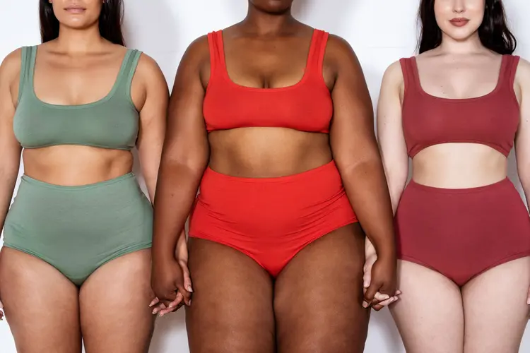 Cropped shot of a three multi-ethnic females of different sizes in lingerie on white background. Group of plus size women in lingerie standing together holding hands. (Luis Alvarez/Getty Images)