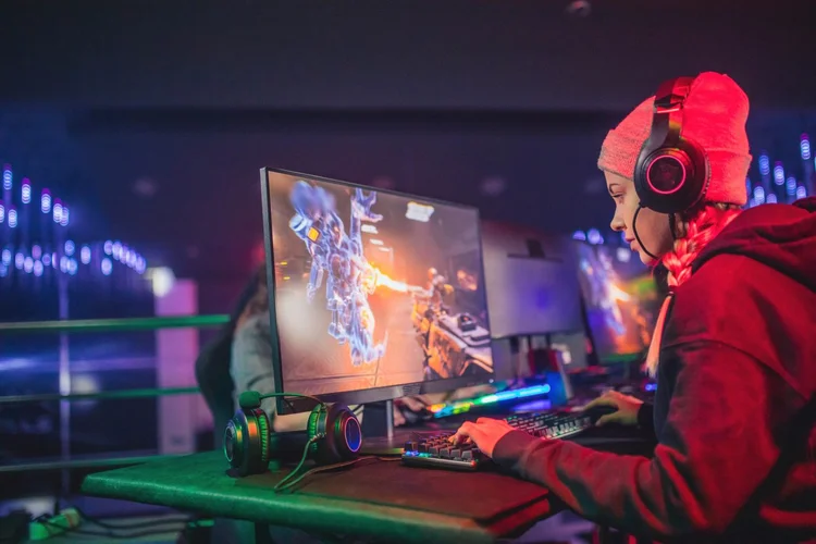 friends compete in playing video games (zeljkosantrac/Getty Images)