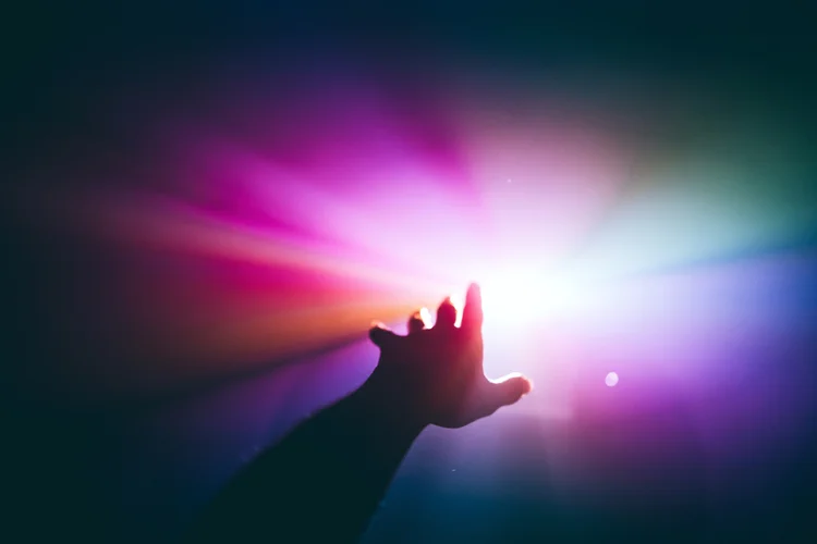 Intergalactic human journey concept with an arm reaching out to the bright vibrant multicolor light. Future and meta human in metaverse, first person view. (Getty Images/Getty Images)