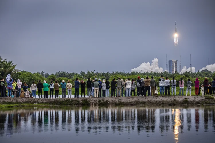 Pessoas observam lançamento do foguete Longa Marcha 8 que levou o Queqiao-2