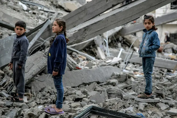 Crianças palestinas entre os escombros de um prédio bombardeado no bairro de Rimal, na cidade de Gaza (Adel ZAANOUN con Cécile FEUILLATRE en Jerusalén /AFP Photo)