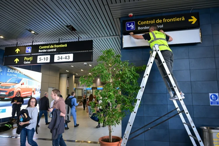 Funcionário troca sinalizações no aeroporto Henri Coanda de Otopeni, na Romênia, em 28 de março de 2024, antes da incoporação parcial do país no espaço Schengen de livre circulação (Ani SANDU com Vessela Sergueva/AFP)