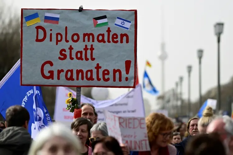 Manifestantes exibem cartaz com a frase "diplomatas ao invés de granadas", durante passeata pela paz organizada em Berlim (Agence France-Presse)