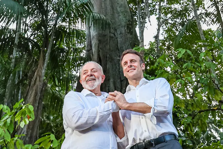 Lula e Macron em Belém na última terça-feira, dia 26, com árvore sumaúma ao fundo: encontro para falar de desafios da Amazônia foi em fábrica de chocolates caseiros que é exemplo de empreendedorismo sustentável (Ricardo Stuckert/Divulgação)