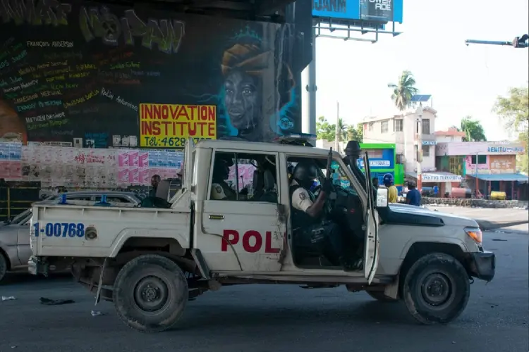 Policiais verificam o perímetro de uma delegacia incendiada no dia anterior em Porto Príncipe, Haiti (AFP Photo)