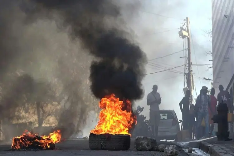 Pneus em chamas perto da principal prisão de Porto Príncipe, no Haiti, após fuga de detentos, em 3 de março de 2024 (AFP Photo)