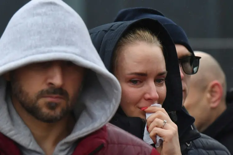 Pessoas choram em um memorial improvisado em frente ao Crocus City Hall, um dia depois de um ataque armado em Krasnogorsk, nos arredores de Moscou, em 23 de março de 2024. (AFP/AFP)