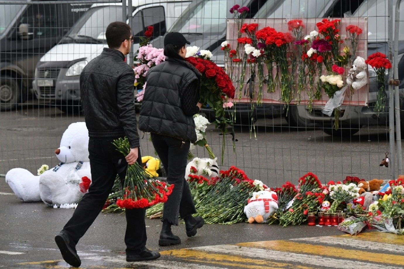 Pessoas levam flores para um memorial improvisado no local do ataque mortal nos arredores de Moscou, em 23 de março de 2024