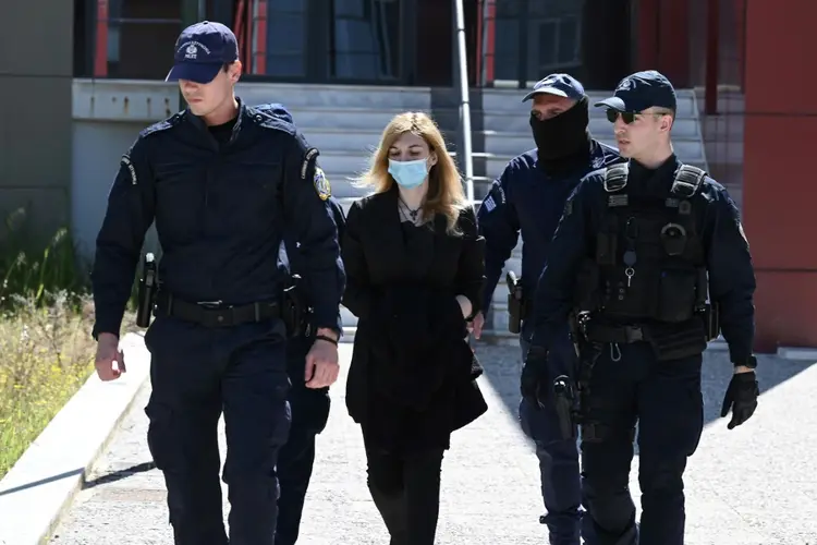 Policiais escoltam Roula Pispirigou, acusada de matar suas três filhas, para um tribunal em Atenas (Agence France-Presse/AFP)