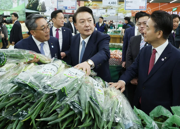 O presidente Yoon Suk Yeol, ao centro, ao visitar um supermercado e checar o preço das cebolinhas, em Seul (Yonhap/AFP)