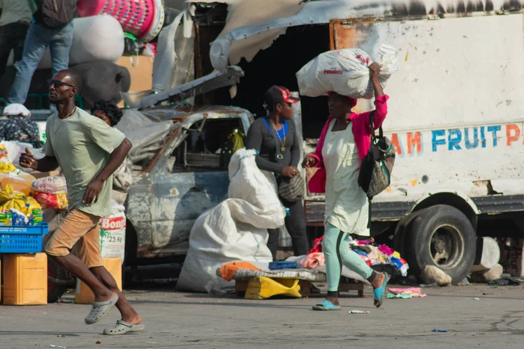 Pessoas correm após relato de tiros em Porto Príncipe, no Haiti, em 13 de abril (Clarens Siffroy/AFP)