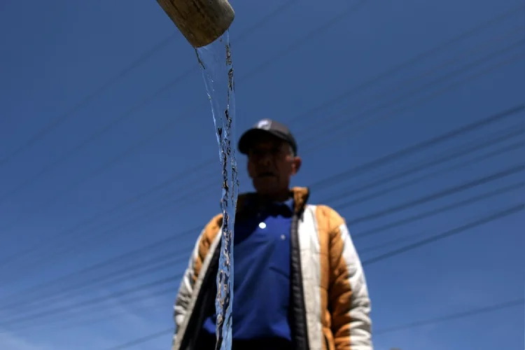 Um homem coleta água com baldes antes do corte do serviço em La Calera, município vizinho de Bogotá (AFP Photo)