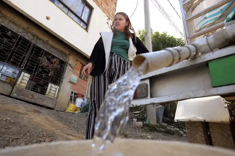 Uma mulher recolhe água potável de um caminhão pipa em La Calera, perto de Bogotá ( Daniel MUÑOZ/AFP Photo)