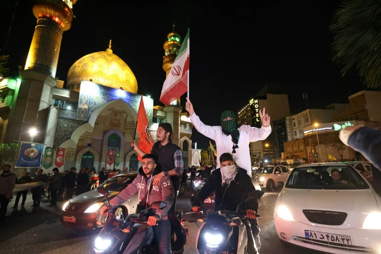 Manifestantes agitam bandeiras de Irã e Palestina em Teerã, em 14 de abril de 2024: reações contraditórias após ataque com drones a Israel (AFP Photo/AFP Photo)
