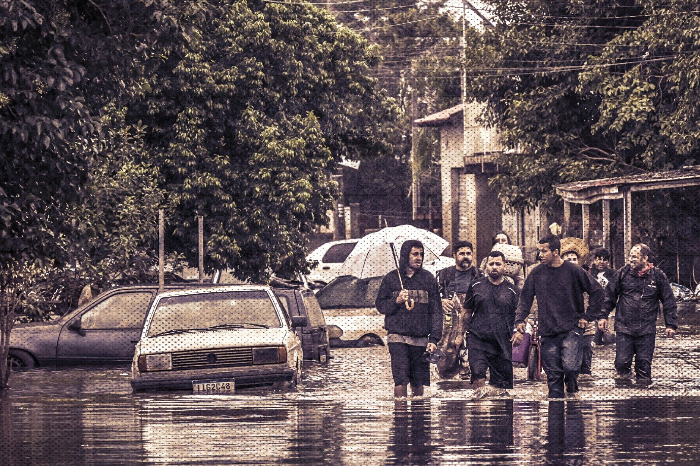 Residents wade through a flooded street in the Harmonia neighborhood in the city of Canoas, Rio Grande do Sul state, Brazil, on May 13, 2024. Brazil's President Luiz Inacio Lula da Silva on Monday put off a state visit to Chile to focus on the historic floods in the south of the country that have left 147 dead. Torrential rains since the beginning of the month in Rio Grande do Sul state have caused rivers to burst their banks, leaving towns and parts of the bustling state capital Porto Alegre under water. Around two million people have been affected, more than 600,000 of whom were forced from their homes due to the disaster, which experts attribute to climate change and the El Nino weather phenomenon. (Photo by NELSON ALMEIDA / AFP)