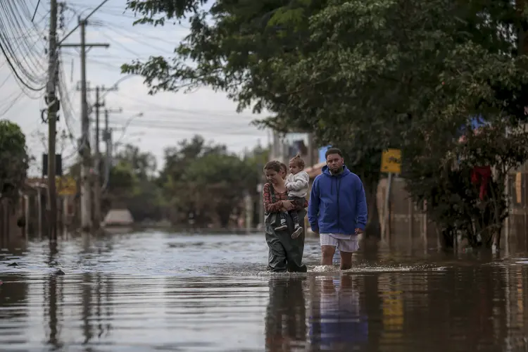 People walk through a flooded street in Eldorado do Sul (RS) (Photo by Anselmo Cunha / AFP)/AFP)