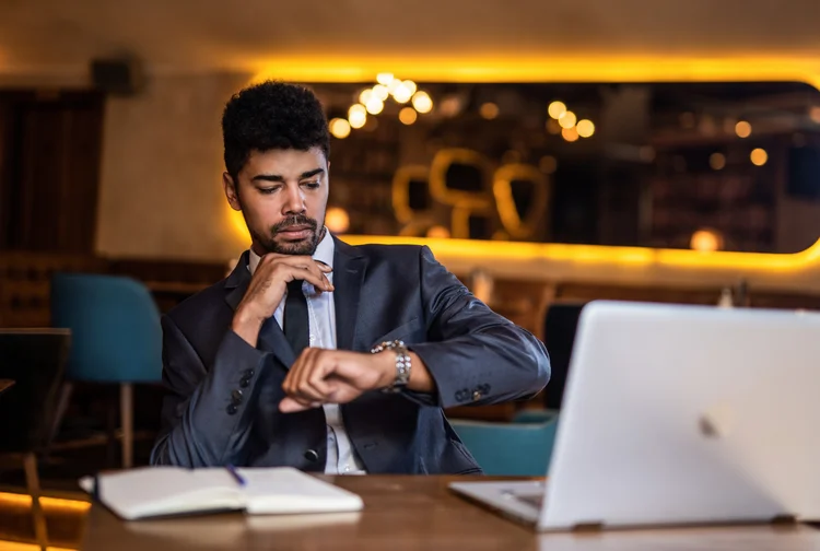 Businessman checking time in a restaurant. (DjelicS/Getty Images)