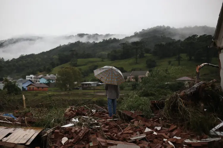 A local resident stands on debris of a house partially destroyed by heavy rains in Sinimbu, in the Vale do Rio Pardo region of Rio Grande do Sul, Brazil on May 1, 2024. The toll after heavy rains in Brazil's southern state of Rio Grande do Sul rose to eight dead and 21 missing, regional authorities said Wednesday. The deluges have displaced approximately 1,400 people in more than 100 municipalities across the state, the majority of whom civil defence officials said had been moved to shelters. (Photo by Anselmo Cunha / AFP) (Photo by ANSELMO CUNHA/AFP via Getty Images) (Anselmo Cunha/AFP)
