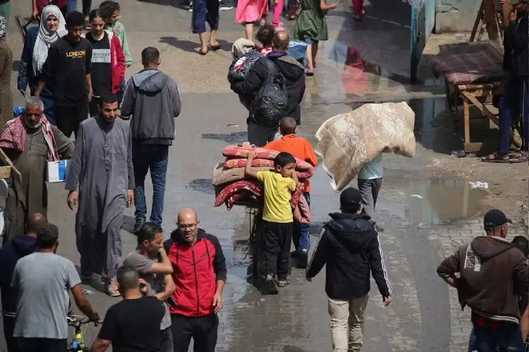 Palestinos deslocados em Rafah, no sul da Faixa de Gaza, carregam seus pertences ao partirem após uma ordem de evacuação do Exército israelense em 6 de maio de 2024, em meio ao conflito em curso entre Israel e o movimento palestino Hamas (AFP)